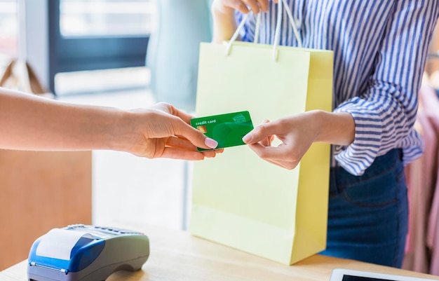 Non-cash transaction concept. Caucasian woman paying with credit card for purchase at clothes showroom