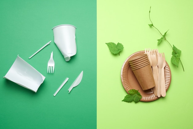 Non-degradable plastic waste from disposable tableware and a set of dishes from environmental recycled materials on a green background