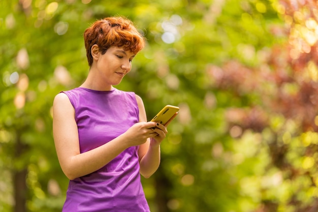 Nonbinary gender person using a cellphone in the park