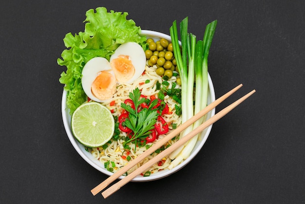 Noodle dish with green onions eggs green pea red hot pepper greens and lime