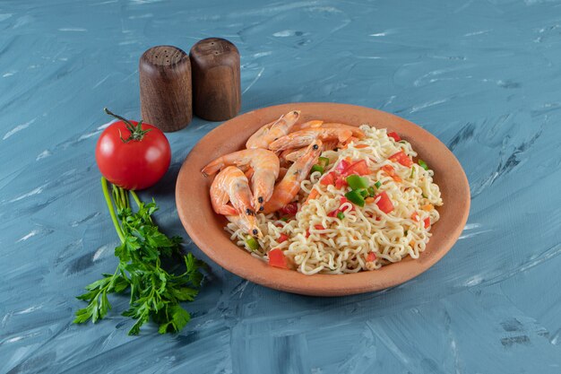 Noodle with meat on a plate next to parsley bunch, tomatoes and salt, on the marble surface.