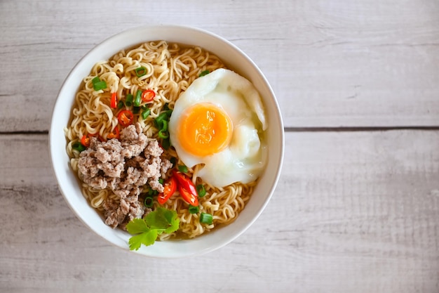 Noodles bowl with boiled egg minced pork vegetable spring onion lemon lime lettuce celery and chili on table food instant noodles cooking tasty eating with bowl noodle soup