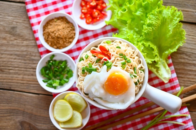 Noodles bowl with boiled egg minced pork vegetable spring onion lemon lime lettuce celery and chili on table food noodle soup instant noodles cooking tasty eating with plate