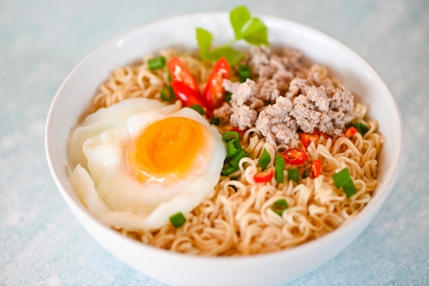 Noodles bowl with boiled egg minced pork vegetable spring onion lemon on table food instant noodles cooking tasty eating with bowl noodle soup