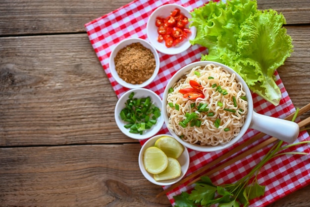 Noodles bowl with vegetable spring onion lemon lime lettuce celery and chili on table food instant noodles cooking tasty eating with bowl noodle soup