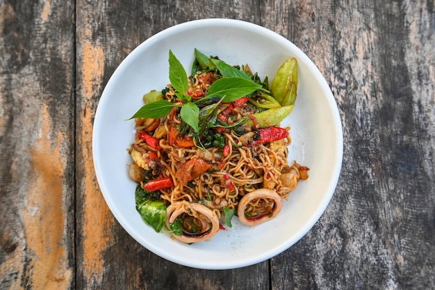 Noodles plate with instant noodles stir fried with vegetables herb spicy tasty appetizing asian noodles mix seafood stir fried squid with basil and chilli pepper