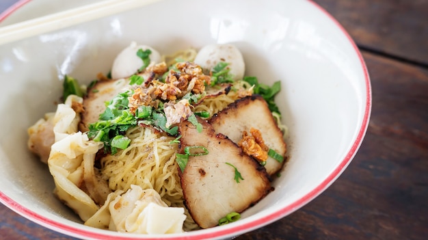 Noodles with pork on a wooden background (Thai noodles).