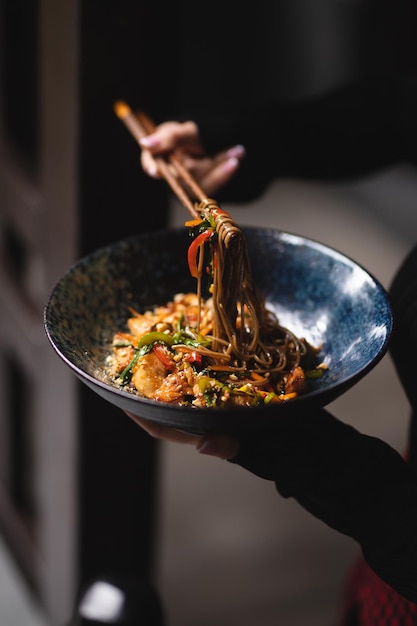 Noodles with seafood and vegetables on a dark background. Asian food