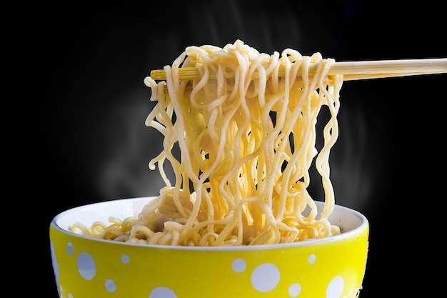 noodles with steam and smoke in a bowl on black background. Top view, Asian food on the table