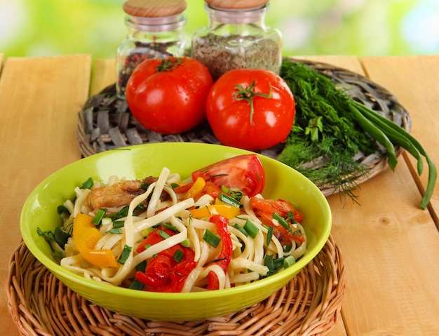 Noodles with vegetables in wok on nature background