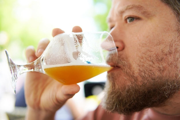 Nordic bearded man drinking beer in a glass outdoors in summertime