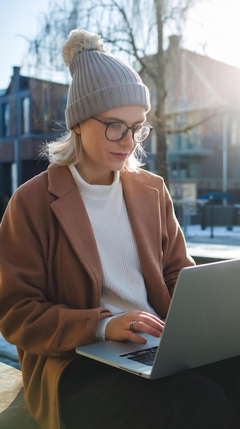 Nordic person working on a laptop outside in the sunshine