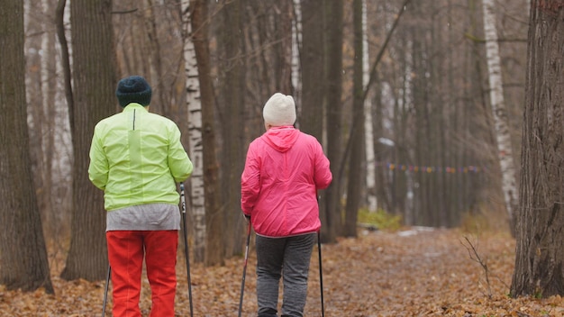 Nordic walking for elderly women outdoor  two senior ladies have training outdoor  rear view