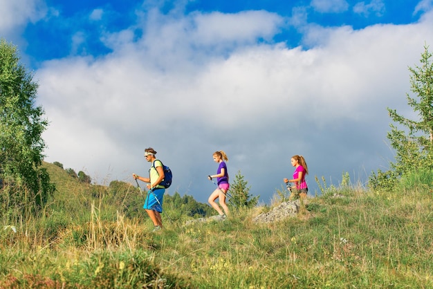 Nordic walking instructor with two girls on mountain trail