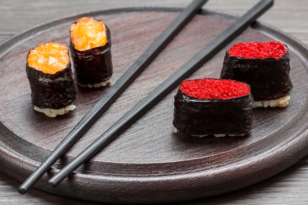 Nori sushi with caviar black chopsticks on cutting board