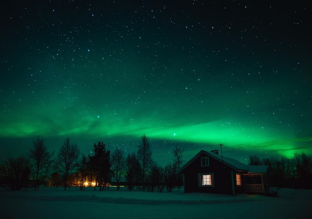 Northern lights Aurora Borealis over snowedin cottage in Lapland village Finland