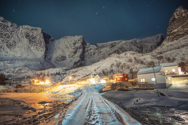 Norwegian colorful village surrounded snow mountain with starry at night