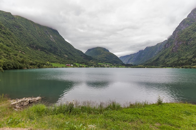 Norwegian fjord and mountains surrounded by clouds, ideal fjord reflection in clear water.