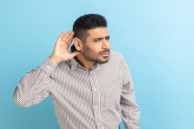 Nosy businessman with beard holding hand near ear listening to interesting talks and private secrets