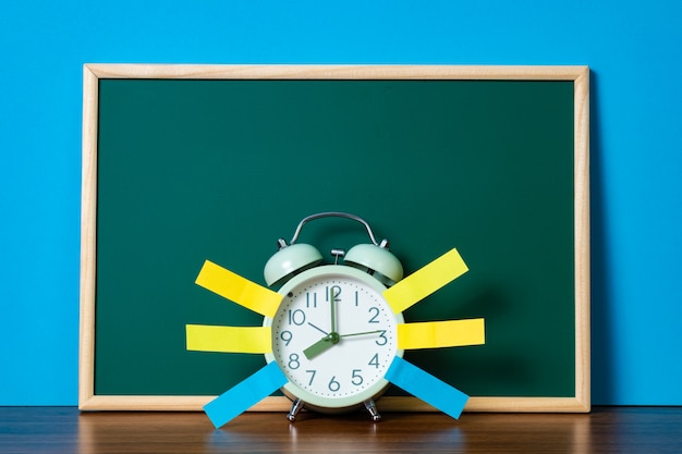 Note paper sticky and vintage alarm clock and blank green chalkboard