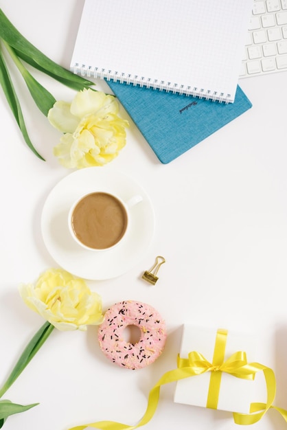 Notebook for daily planning with breakfast serving on a white background cup of coffee donut flowers