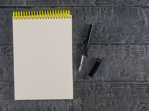 Notebook and fountain pen on a dark table top view. Place for your text.