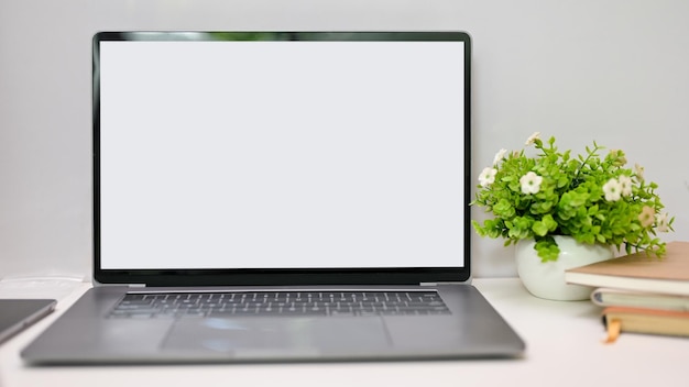 Notebook laptop white screen mockup is on the table with decor closeup workspace