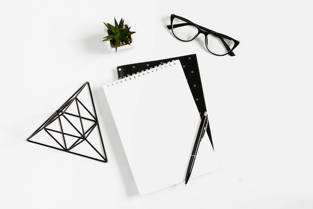 Notebook, pen, eye glasses lie on a white background