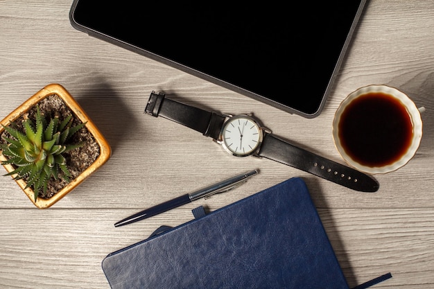 Notebook pen men's watch cup of coffee houseplant in a pot