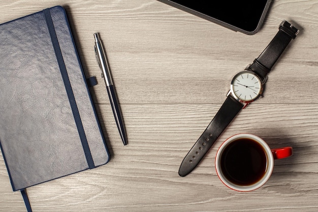 Notebook pen men's watch cup of coffee and tablet