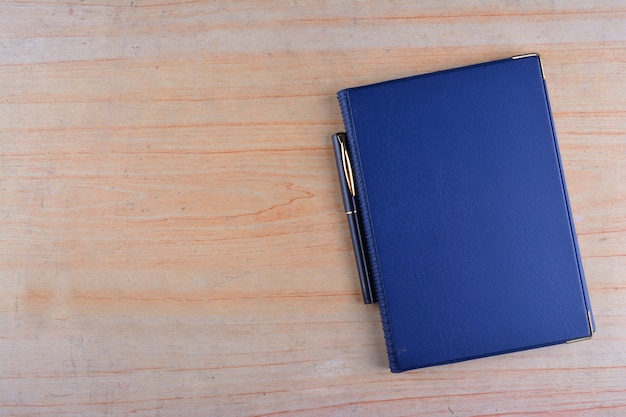 Notebook and pen over a wooden background