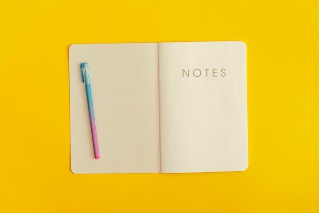 Notebook and pen on yellow background. Top view. Flat lay. Back to school concept.