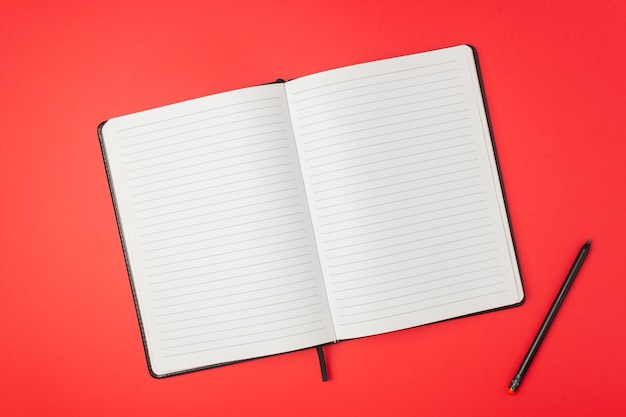 Notebook on a red table. Design. Minimal concept. Flat lay.