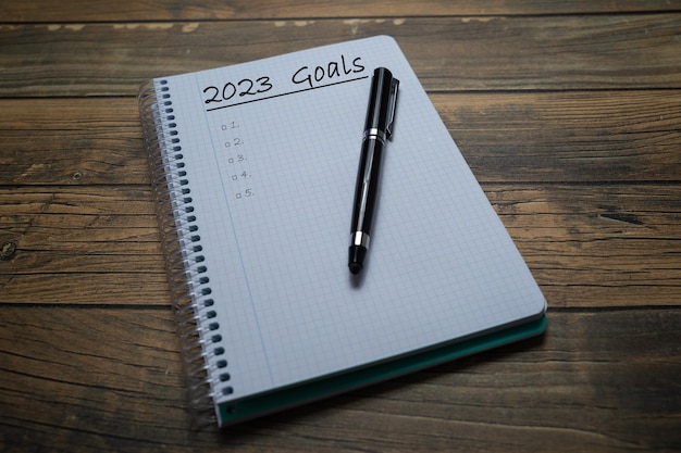 Notebook sheet written 2023 to put the resolutions and objectives of the year with a pen and wooden background