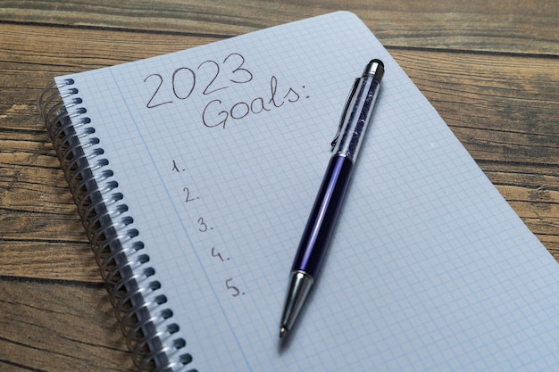 Notebook sheet written 2023 to put the resolutions and objectives of the year with a pen and wooden background