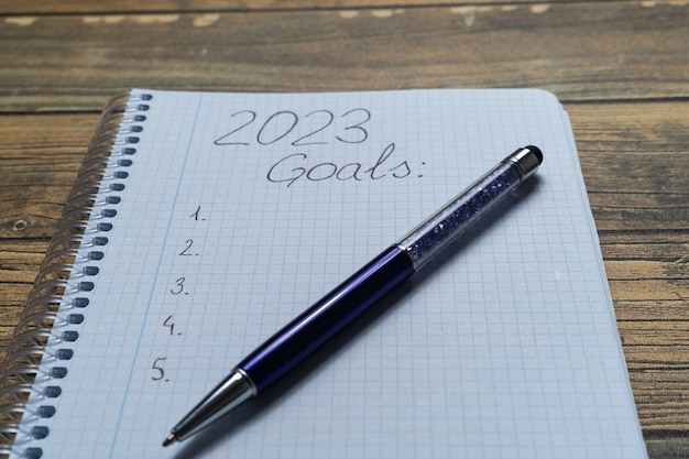 Notebook sheet written 2023 to put the resolutions and objectives of the year with a pen and wooden background