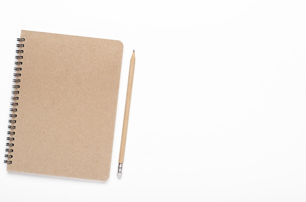 Notebook on a spiral of kraft paper with a pencil on a white background. Office desk, stationery. Copy space, top view, flat lay.