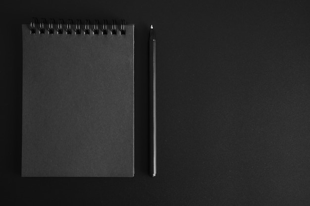 Notebook on a spring with black sheets and a pen on black