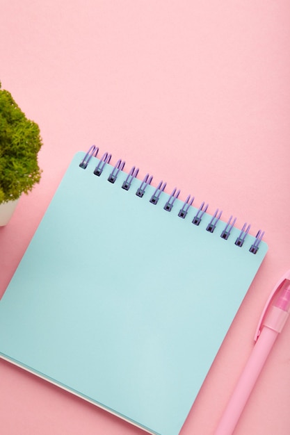 A notebook with a blank page and pen on pink background Copy space layout mockup