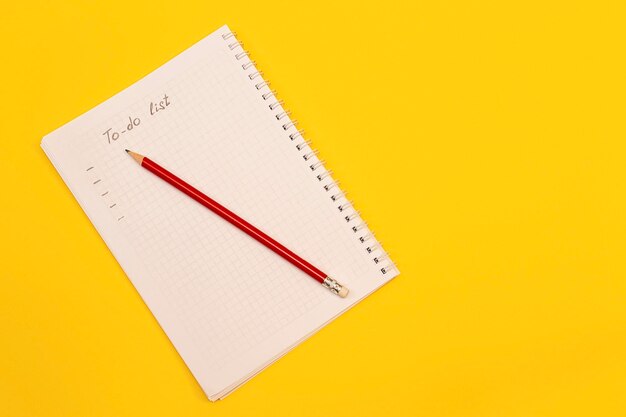 Notebook with blank sheet and pencil on yellow background