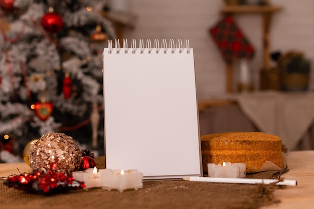 notebook with empty pages on a wooden table in the kitchen background of a Christmas tree. New Year