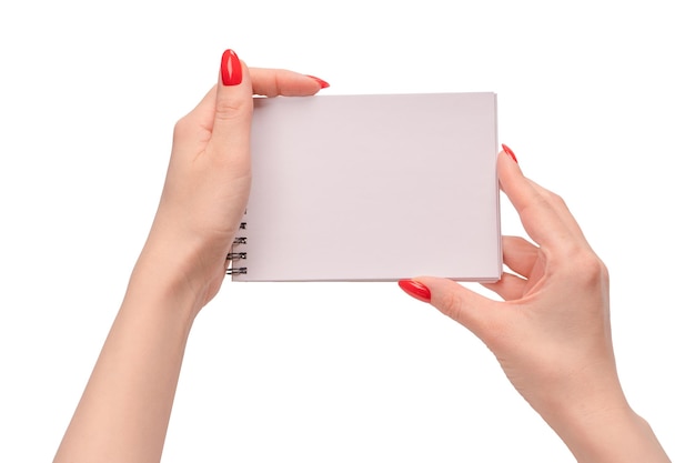 A notebook with empty white paper in woman hands with red nails