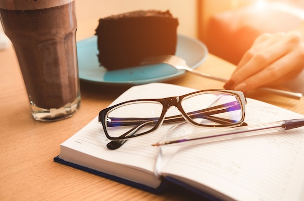 Notebook with glasses, cake and coffee. Working or planning concept