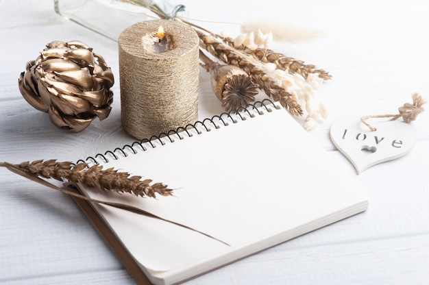 notebook with golden dry flowers and lit candle