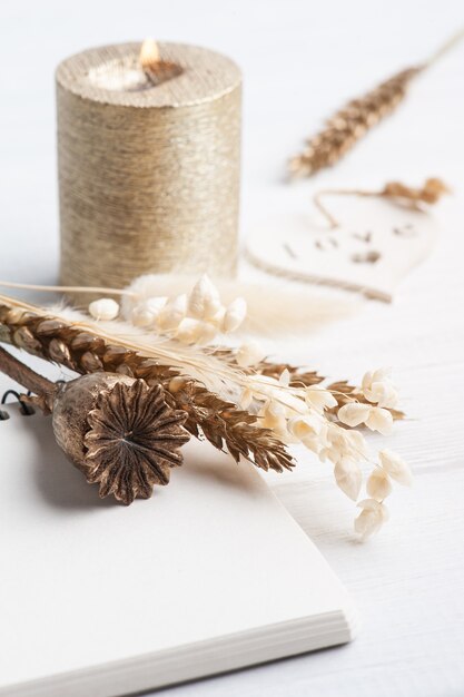 notebook with golden dry flowers and lit candle