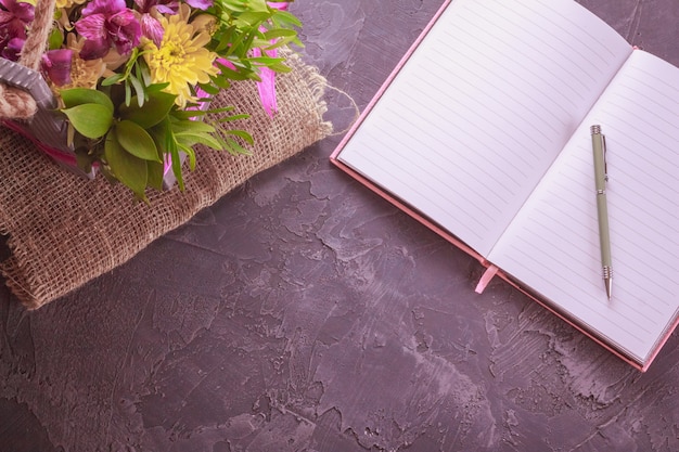 Notebook with pen and a bouquet of flowers