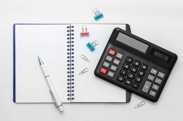 Notebook with pen and calculator on white background