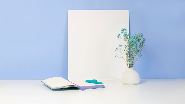 A notebook with a pen lie on a white table with a vase. Preparation for writing the text.