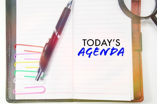 A notebook with a pen and a paper that says today's agenda.