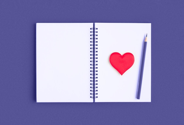 Notebook with pencil, red heart. Open notebook on violet, purple color background, spiral notepad. Top view. Notepad with blank white page for write, office flat lay. Copy Space. Valentine Day, Love